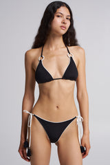 Woman wearing a black bikini with white strings on a gray background