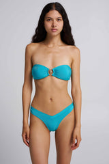 Woman wearing a turquoise bikini against a plain background