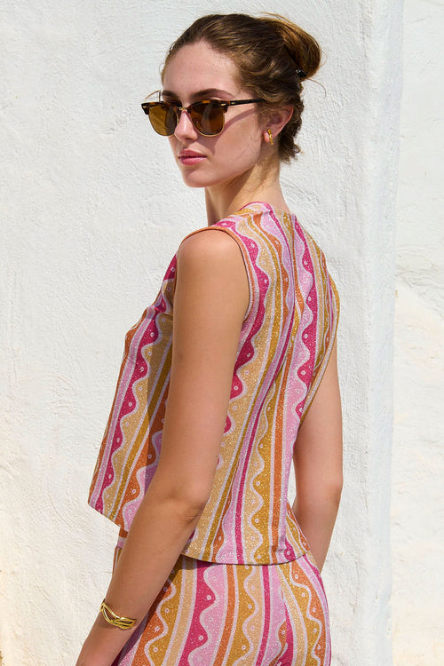 Woman wearing a colorful patterned dress against a white wall