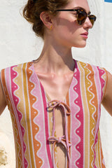 Woman wearing a sleeveless, patterned top with a white background